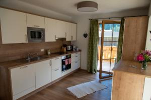 a kitchen with white cabinets and a sink at Ferienwohnung Lech'tl in Steeg
