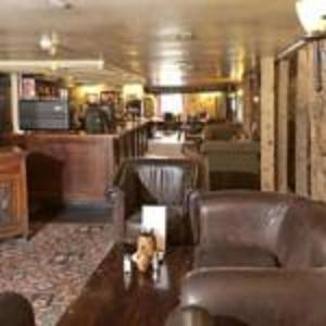 una sala de estar con sillas de cuero y un bar en Old Ferry Boat by Greene King Inns en St Ives