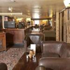 una sala de estar con sillas de cuero y un bar en Old Ferry Boat by Greene King Inns, en St Ives