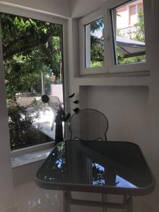 a glass table and a chair in front of two windows at House Filomena in Rab