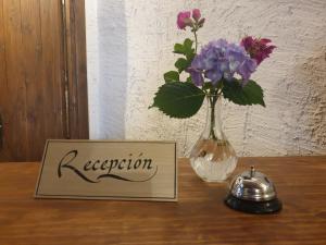 a vase of flowers and a sign on a table at Hotel Labranza in San Martín de Valdeiglesias