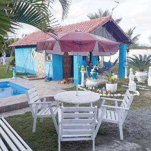 - une table et des chaises avec un parasol en face d'une maison dans l'établissement Pousada da Praia, à Itaipuaçu