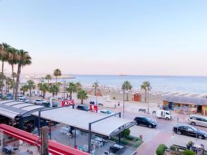 a parking lot next to the beach with palm trees at Beach Front Apartment in Larnaka