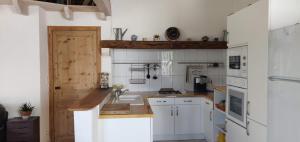 uma pequena cozinha com armários brancos e um lavatório em Chambres d'hôtes Les Sarments em Saint-Pierre-dʼOléron