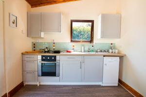 a kitchen with white cabinets and a sink and a window at The Lodge @ Caeaugwynion in Pencader