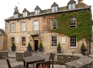 - un ancien bâtiment en pierre avec une table devant dans l'établissement Old Manse Hotel by Greene King Inns, à Bourton-on-the-Water