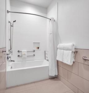 La salle de bains blanche est pourvue d'une baignoire et d'une douche. dans l'établissement Ayres Hotel Vista Carlsbad, à Vista