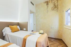 バルセロナにあるEn Ville Boutique Apartments Boqueria Marketのベッドルーム1室(ベッド2台、ベッドに帽子付)