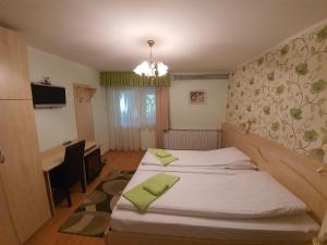 a room with two beds and a desk and a television at Platán Szálláshely in Sándorfalva
