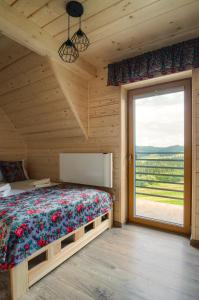 a bedroom with a bed and a large window at Domki Sówka in Dursztyn