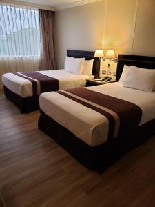 a hotel room with two beds and a window at Hotel Diego de Almagro La Serena in La Serena