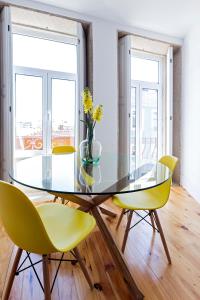 a glass dining table and yellow chairs in a room at Bom Porto Apartments in Porto