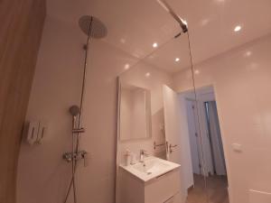 een badkamer met een wastafel en een douche met een spiegel bij Sun and Beach II AC Wifi 90mts from the Beach in Portimão