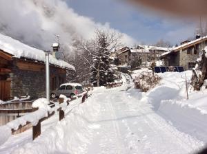 a street covered in snow with a car driving down it at La Maison du Guide in Rhemes-Saint-Georges