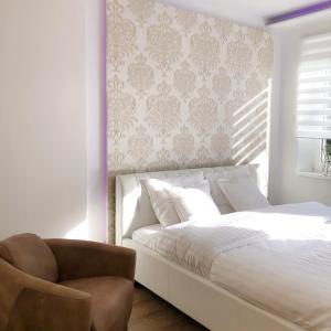 een slaapkamer met een wit bed en een stoel bij VIP 67 in Eupen