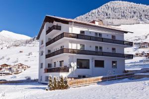 a white building in the snow with a mountain at Amontanara in Nauders