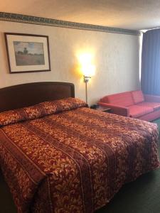 a hotel room with a bed and a pink chair at Fairborn Hotel and Inn in Fairborn