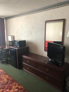a hotel room with a television and a dresser with a mirror at Fairborn Hotel and Inn in Fairborn