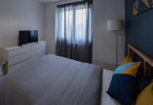 1 dormitorio con 1 cama, TV y ventana en Appartement 3 chambres - Parking - Wifi - Buanderie - Jardin, en Brest