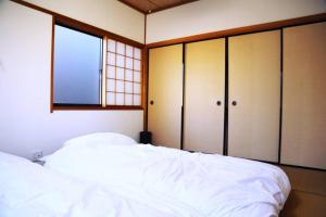 a bedroom with a white bed and a window at Tsukuyomi Chuodori in Kanazawa
