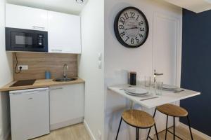 a kitchen with a small table and a clock on the wall at Studio Cosy - Parking - Wifi - Buanderie - Jardin in Brest