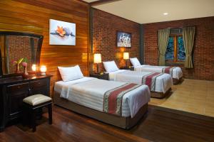 
a hotel room with two beds and two lamps at Jambuluwuk Convention Hall & Resort Batu in Batu
