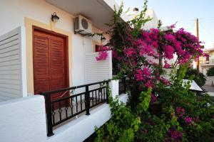 ein Gebäude mit rosa Blumen und einer roten Tür in der Unterkunft Thalia Hotel in Palekastro