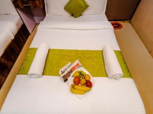 two beds with a bowl of fruit on them at Hotel Alfa Heritage in Mumbai