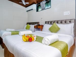 um quarto com três camas com bananas e fruta em Hotel Alfa Heritage em Mumbai
