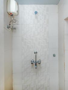 a shower with a white tiled wall at Hotel Alfa Heritage in Mumbai