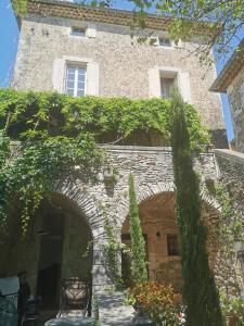 a stone building with an archway and ivy at Domaine d'Audabiac in Lussan