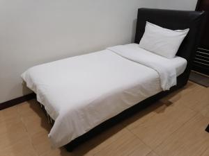 a white bed with a black headboard and white sheets at Fargo Boutique Hotel in Kuantan