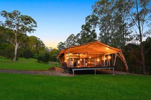 Starry Nights Luxury Camping في Woombye: مبنى كبير به انارة في حقل اخضر