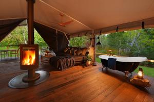 a tent with a bath tub on a wooden floor at Starry Nights Luxury Camping in Woombye