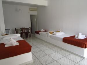 a hotel room with two beds and a table at Paradise Apartments Studios in Mylopotas