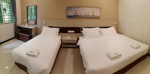 two beds in a hotel room with white sheets at Hemingway Cottage 海明威度假屋 in Semporna