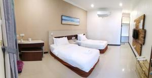 a hotel room with two beds and a television at Hemingway Cottage 海明威度假屋 in Semporna