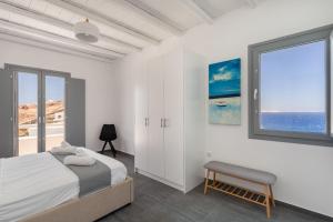a white bedroom with a bed and a window at Nikoi Villas in Mikonos