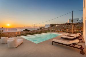 a villa with a swimming pool and a sunset at Nikoi Villas in Mikonos