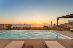 a swimming pool with a sunset in the background at Nikoi Villas in Mikonos