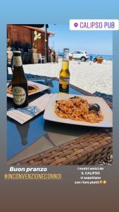 a table with two bottles of beer and a plate of food at Scilla's Dream in Scilla