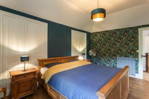 - une chambre dotée d'un lit avec des draps bleus et des murs verts dans l'établissement Domaine La Rose, à Caylus