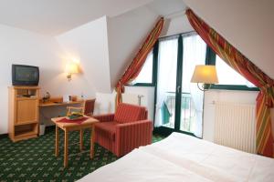 ein Hotelzimmer mit einem Bett, einem Stuhl und einem Fernseher in der Unterkunft Etzhorner Krug in Oldenburg