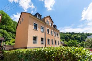 a large brown building with trees in the background at Haus am Malerweg in Bad Schandau