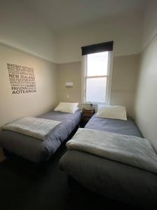 twee bedden in een kamer met een raam bij Hokitika Pioneer Hotel in Hokitika