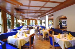ティーレスにあるHotel Pinéの白いテーブルと青い椅子が備わるレストラン