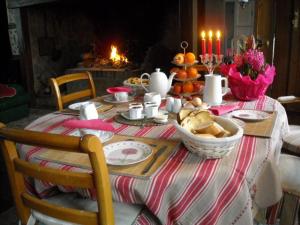 einen Tisch mit einem Tischtuch mit Essen und Kerzen in der Unterkunft Chambres d'hôtes ''La Grand' Maison'' in Escalles