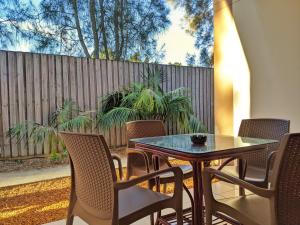 un patio con mesa, sillas y una valla en Novena Palms Motel en Brisbane
