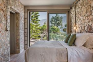 a bedroom with a large bed and a large window at Ploes Luxury Cottages in Kefallonia