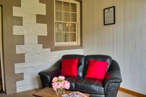 un sofá de cuero con almohadas rojas en la sala de estar. en BIG4 Cape Jervis Accommodation & Caravan Park en Cape Jervis